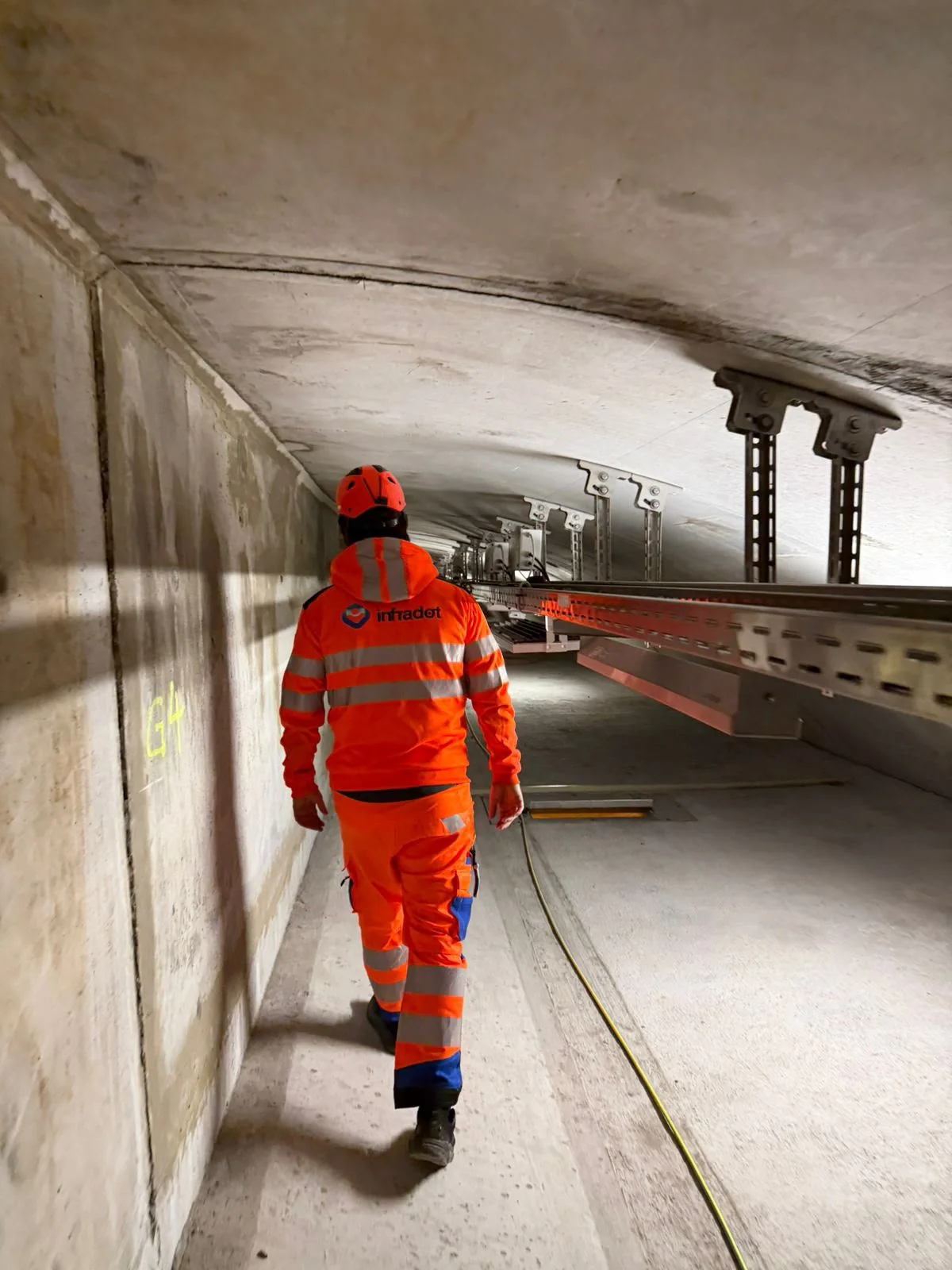 InfraDot-Mitarbeiter geht in einem Tunnel an einer Kabeltrasse entlang